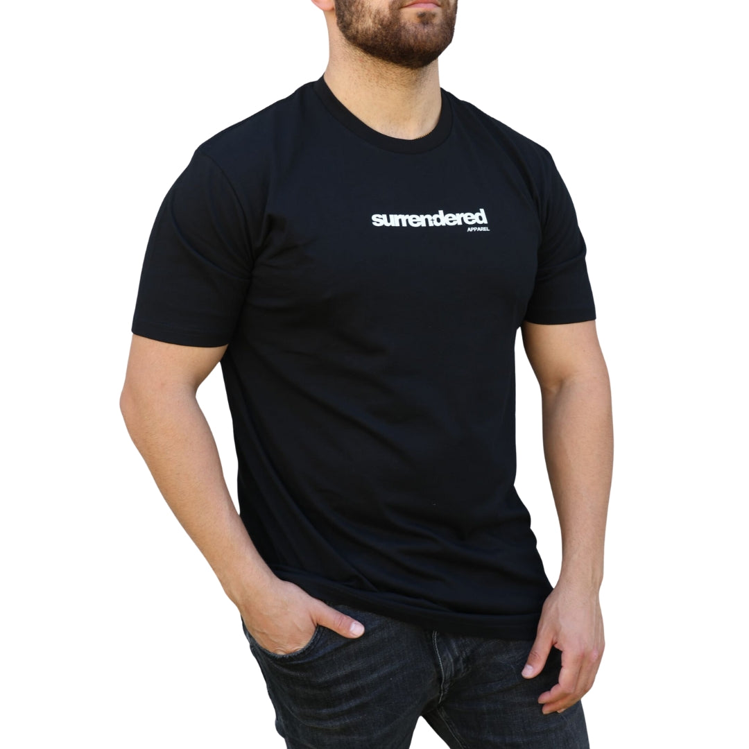 Bearded Man wearing a Surrendered Apparel Christian Crew Neck T-shirt in Black. Light Cotton shirt in black, white Surrendered Apparel logo across the front of the chest. Man is wearing black Jeans